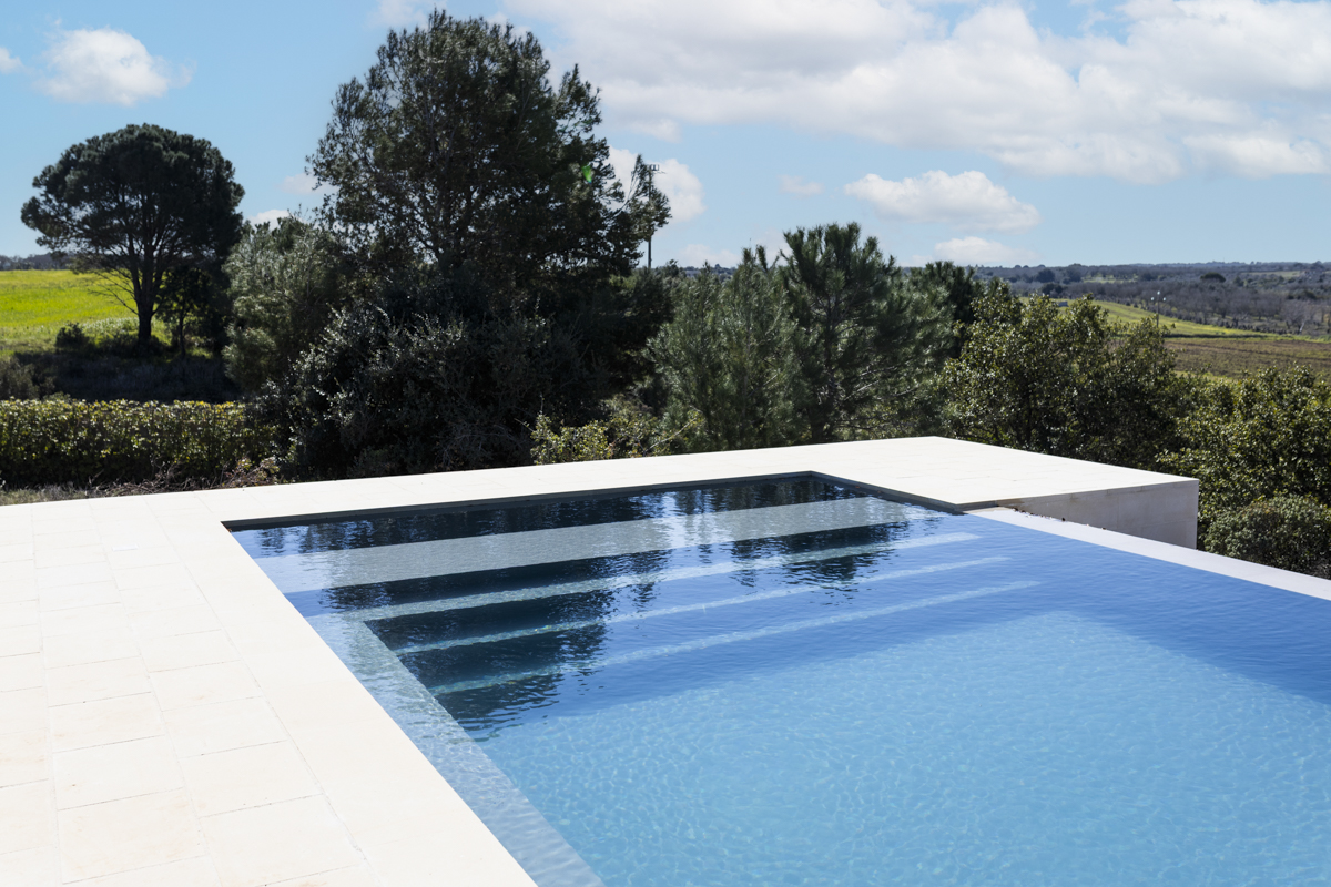 Una piscina blu scintillante circondata da sedie a sdraio e palme